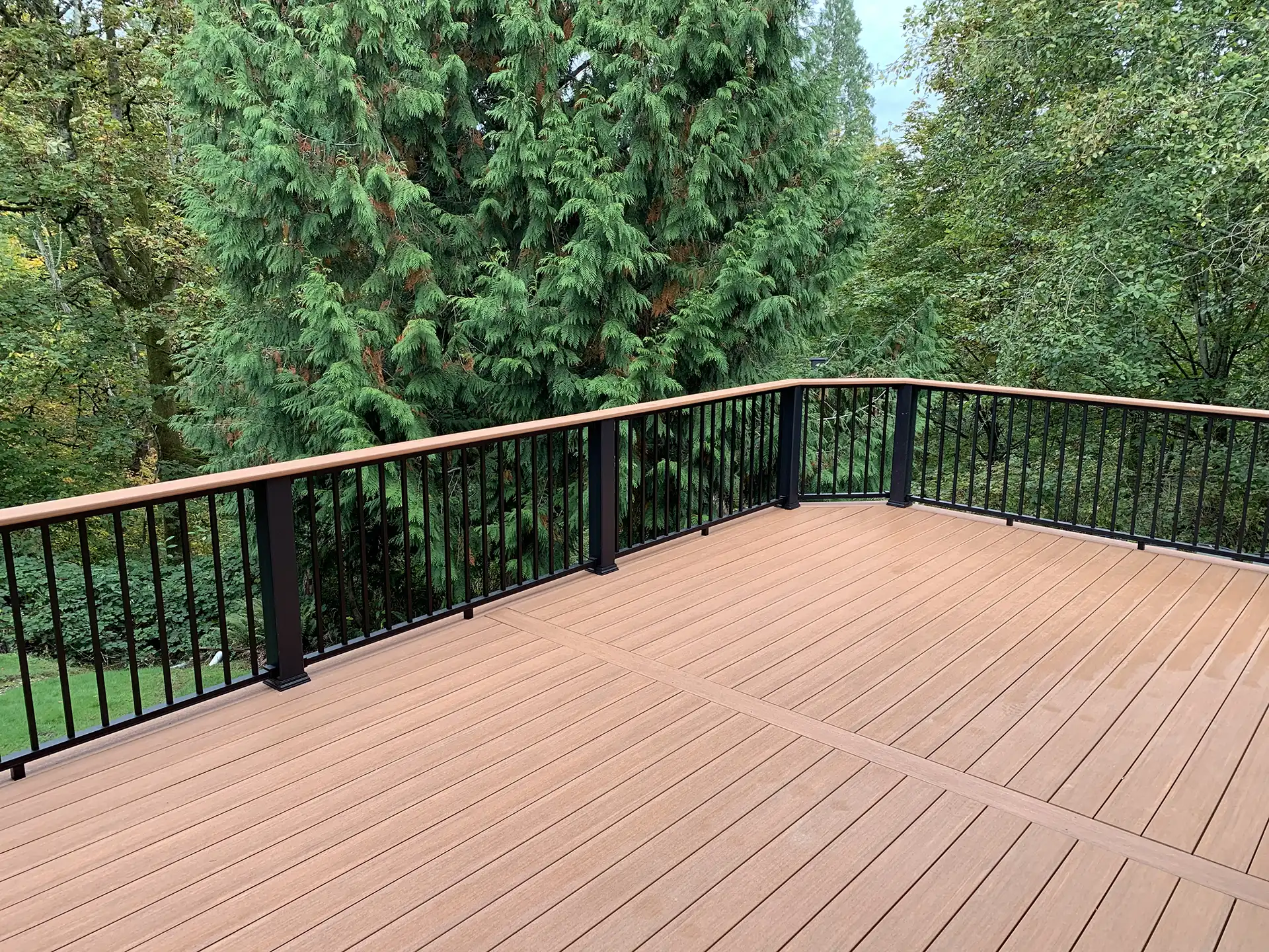 photo of a composite deck with deck railing overlooking a wooded area - Composite Decking vs. Traditional Wood Decking - Composite decking contractor in Greater Seattle Area