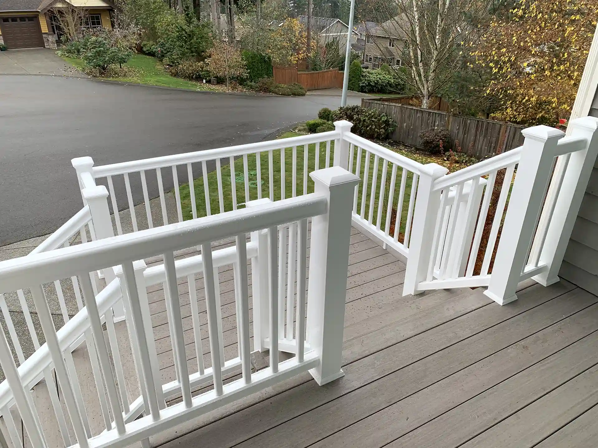 Elevated composite deck with white deck railing and steps leading to the ground - Trex Deck Contractors near me - Composite Decking Company near me